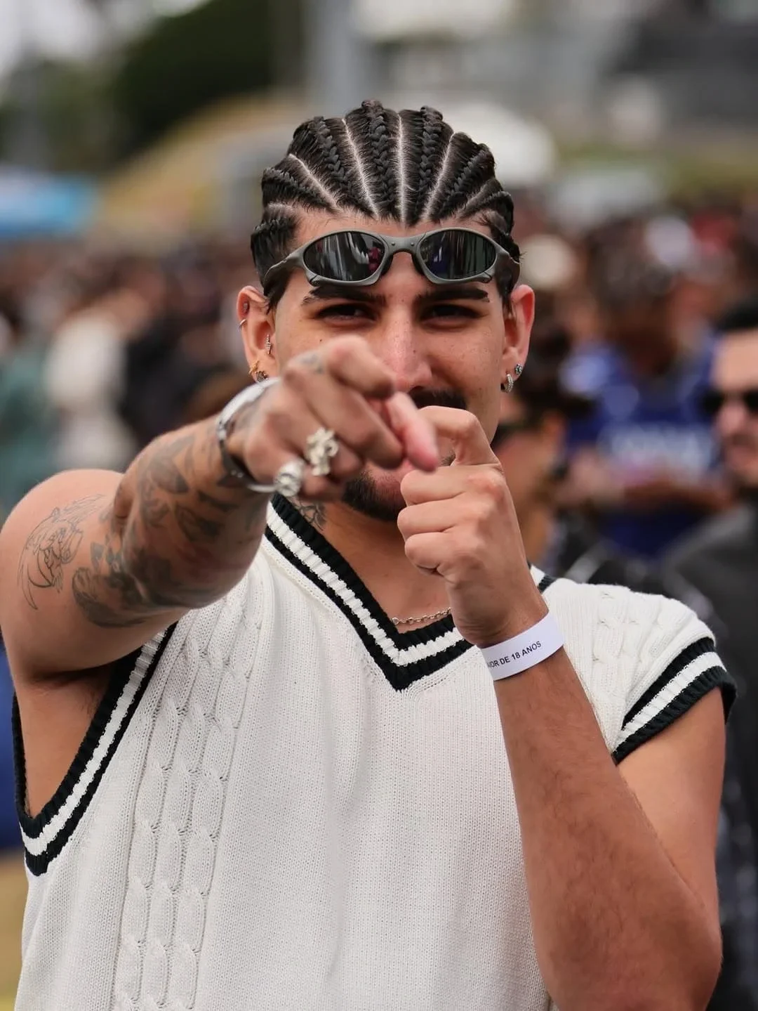 Rapaz de óculos escuro apontando pra câmera num festival